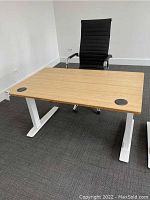 Front view of desk and chair setup showing bamboo top, white base and black chair.