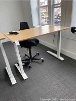 Side view of bamboo tabletop on white adjustable legs with chair behind