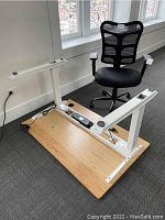 Full view of desk frame and bamboo top on floor with accompanying chair