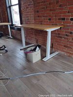 View of desk at medium height in front of brick wall with HÅG chair visible