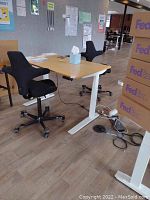 Full view of desk and two chairs in open office environment, showing motorized frame and bamboo top