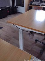 Bamboo desk top corner, white steel leg, partial view of chair wheel