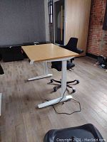 Full view of bamboo top desk on white steel frame paired with black HAG chair