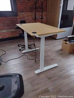 Front view of bamboo top desk on white steel legs with black office chair behind