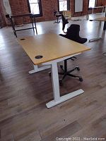 Full view of bamboo desktop and white T-frame legs with HAG chair behind