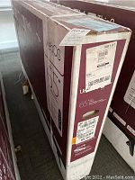 Full view of boxed LG 65" TV showing webOS 65" branding and sealed packaging