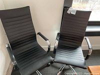Two black Winport office chairs with ribbed seats and backs, padded armrests, and chrome metal bases with caster wheels, viewed from the front and top angles. One chair shows a slight tear in the seat upholstery.