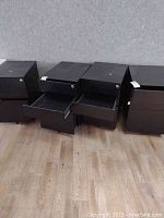 Front view of two black three-drawer file cabinets showing open middle and bottom drawers to display drawer size and construction.