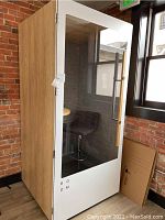 Front view of booth showing wood-grain exterior, white frame, glass door with ROOM logo