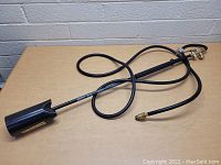Full view of the Blaze torch lying on a wood surface showing the torch, hose, and fittings.