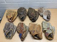 Eight old baseball gloves arranged two rows, showing different colors and wear levels.
