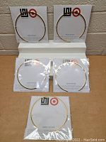 Front view of two gold-tone thin metal choker necklaces attached to branded cards on display shelf.