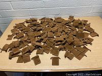 Large quantity of small brown suede-like drawstring pouches spread out on a table.