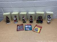 Photo showing six International Santa figurines displayed in front of their original boxes and three booklets on the floor