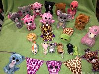 Photo of Ty Beanie Boos plush toys arranged on green fabric, showing variety of animals and colors.