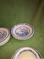 Close-up of several small bowls showing quail bird design in blue and white porcelain with scalloped edges.