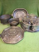Full set of vintage Guardian cast aluminum pans and glass lids on green cloth background.