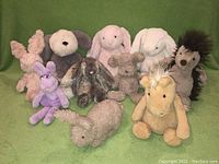 Image shows nine assorted JellyCat London stuffed animals placed on green fabric background