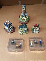 Photo showing all components of the Liberty Falls collection lot including four miniature buildings and pewter figurines in plastic cases.