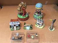 Full view of all Liberty Falls collectible items laid out on surface including wind-up music boxes, buildings, bridge, and pewter figures in original boxes.