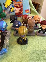 Photo of Marvel Avengers collectible bobblehead or figurine toys showing characters Thanos, Groot, Iron Man, Captain America, Black Panther, Black Widow, Scarlet Witch, Nebula