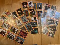 Photo showing a collection of New Kids On The Block trading cards arranged and protected in plastic sleeves, featuring multiple images of individual band members and group shots with colorful geometric border designs.