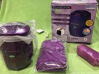 Purple Remington paraffin wax warmer with cable, sealed gloves/mittens in plastic and roll of paraffin wax, the warmer and accessories shown alongside original packaging box.
