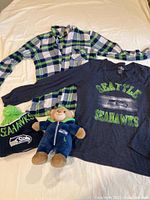 Lot contents showing all items including both shirts, Seahawks beanie hat, and small plush bear in Seahawks outfit.