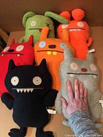 Overview of six Ugly Dolls plush toys in various colors and designs on a brown surface.