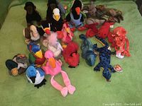 Photo showing a variety of Ty Beanie Babies including birds and sea creatures arranged on a green background.