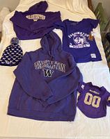 Full lot of University of Washington clothing laid out including hoodies, t-shirts, hat and pet jersey.