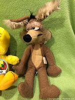Full view of 1971 Wiley Coyote plush with brown, tan fur and distinctive facial features sitting on green background.
