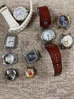 Lot of ten assorted watches and watch parts including Marc Jacobs watch with leather strap, white plastic strap watch, and other watch faces and cases.