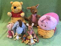 Photo of whole Winnie the Pooh and Friends plush toy lot arranged on green fabric background.