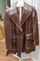 Full front view of brown vintage men's leather coat showing double-breasted buttons, wide lapels, and flap pockets.