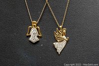Close-up photo showing detailed angel pendants on gold-tone chains, both adorned with clear stones and marked 925 silver.