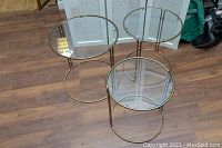 Three round brass finish nesting tables arranged together on wood floor