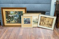 Four framed prints on floor with couch background showing various sizes and frame styles
