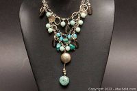 Necklace displayed on a black bust showing the three strands and hanging pendants.