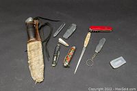 Full view of all knives and leather sheath on black background