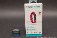 Fitbit Alta HR box with pink fitness wristband image and Walk-A-Jog digital meter side by side on black background.