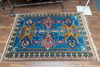 Full view of rug laid flat on wooden floor showing overall pattern and colors