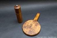 Peugeot wooden pepper mill and Dansk cheese board shown upright on black background