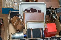 Photo showing assorted vintage items including pewter mug, leather canteen, Kodak metal tray, various glassware, photo frames, and books/albums.