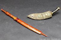 Two ceremonial Asian dagger sheaths, one wooden with brass accents and one ornate silver filigree with stone insets.