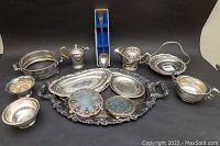 Full lot view showing various silver plated servingware including bowls, trays, teapot, gravy boat, and souvenir spoon.