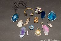 Overview of all 10 gemstone pendants and one bracelet on black background, displaying various colors and shapes.