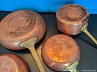 Photo showing underside of all four copper pans revealing hammered and worn copper surfaces.