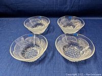 Four clear Nuutajärvi Finland glass bowls shown from top, displaying floral and bubble textured glass design and round shape.