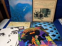 Photo showing six rock albums stacked: Pink Floyd 'Meddle', Grateful Dead 'Workingman's Dead', Buffalo Springfield 'Buffalo Springfield Again', Santana 'Amigos', John Cale 'Songs for Drella', The Who 'Tommy'